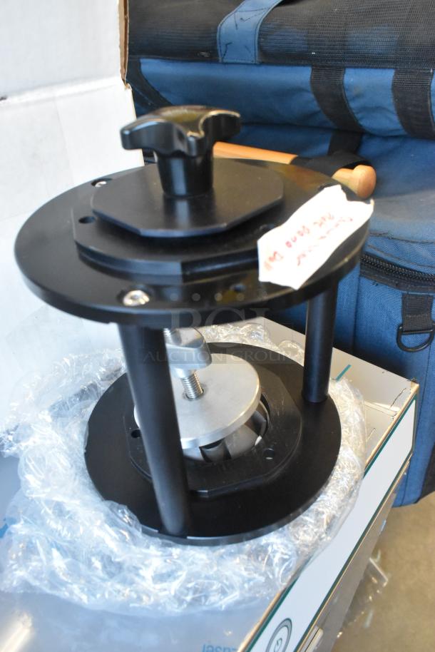 Dana Dolly Camera Riser, black metal, in excellent condition, includes a labeled tag, wrapped in protective plastic.