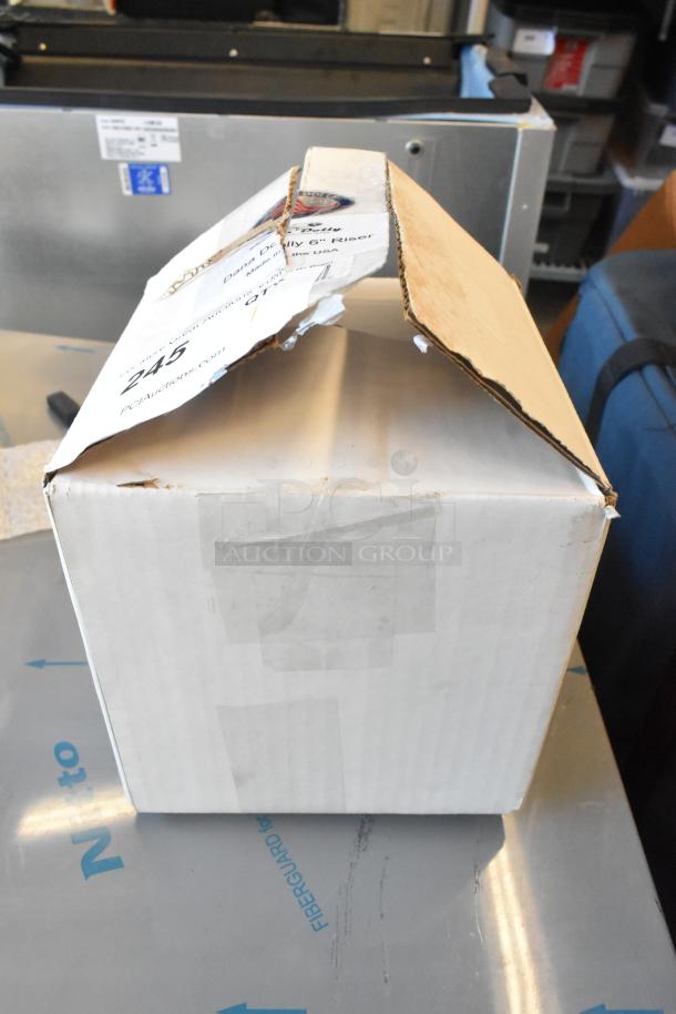 Dana Dolly Camera Riser in damaged cardboard box, showing label with model details and auction info.