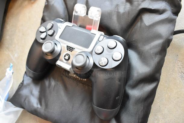 Sony controller with grip on a black cushion, part of Ditogear tech lot for auction. Appears in used condition.