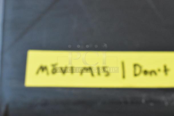 Blurry image of a label with "Mōvi M15" written on it, placed on a dark surface.