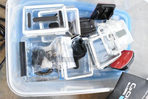 Poly bin containing GoPro accessories, various wires, and poly containers. Includes mounts and adhesive pads in good condition.