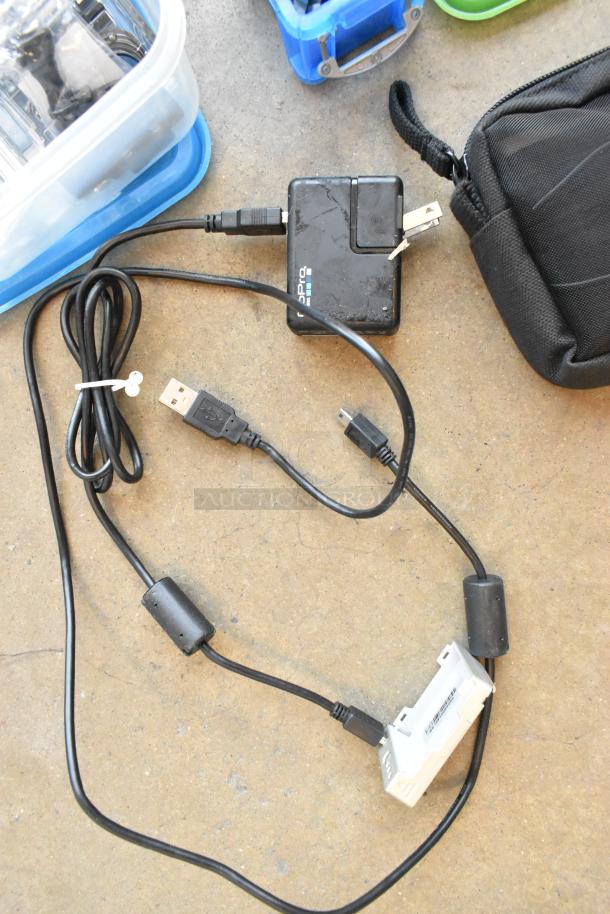 Lot of items including GoPro charger, USB cables, and poly containers in bin. Key accessories for GoPro use.