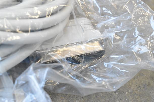 Poly bin with various wires and cables, wrapped in plastic. Items appear used. No visible brand or model markings.
