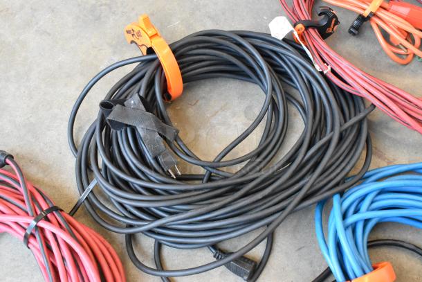 Lot of extension cords in poly bin, includes various colors and lengths, minimal wear, organized with plastic and velcro ties.