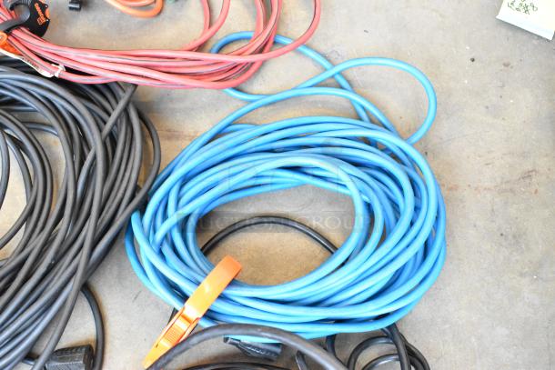 Lot of extension cords in various colors and lengths, coiled on the ground, includes a visible orange clip.