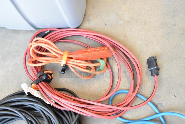 Lot of extension cords in a poly bin, various lengths and colors, some with multi-outlet connectors. Used condition.