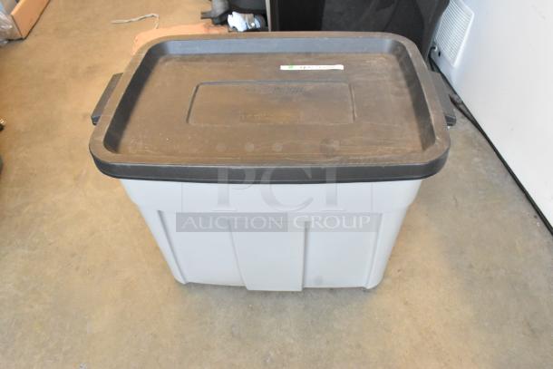 Poly bin containing a lot of extension cords, labeled on the lid. Bin is gray with a black lid, used condition.