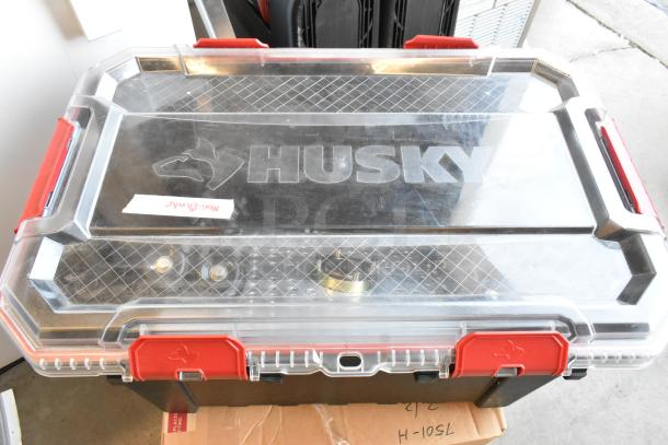 Husky storage box labeled "Movi Elevator," clear lid, red latches, robust condition, ideal for secure equipment transport.
