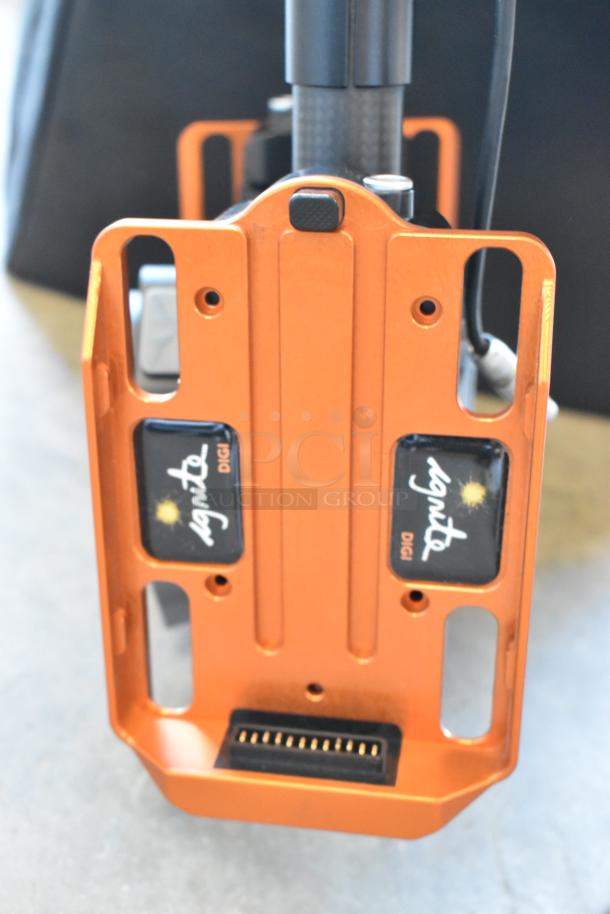 Orange Digi Ignite metal frame with branded labels, features precision slots and connector, appears in a rolling bag.