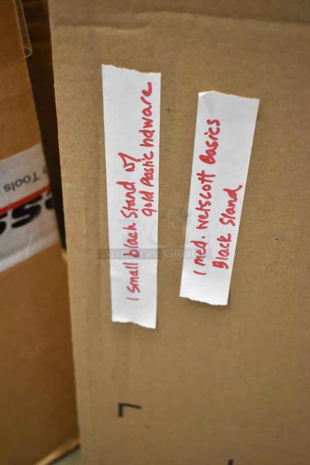 Cardboard box for Westcott Basics Omni Stand, labeled with handwritten notes indicating different stand sizes and materials.