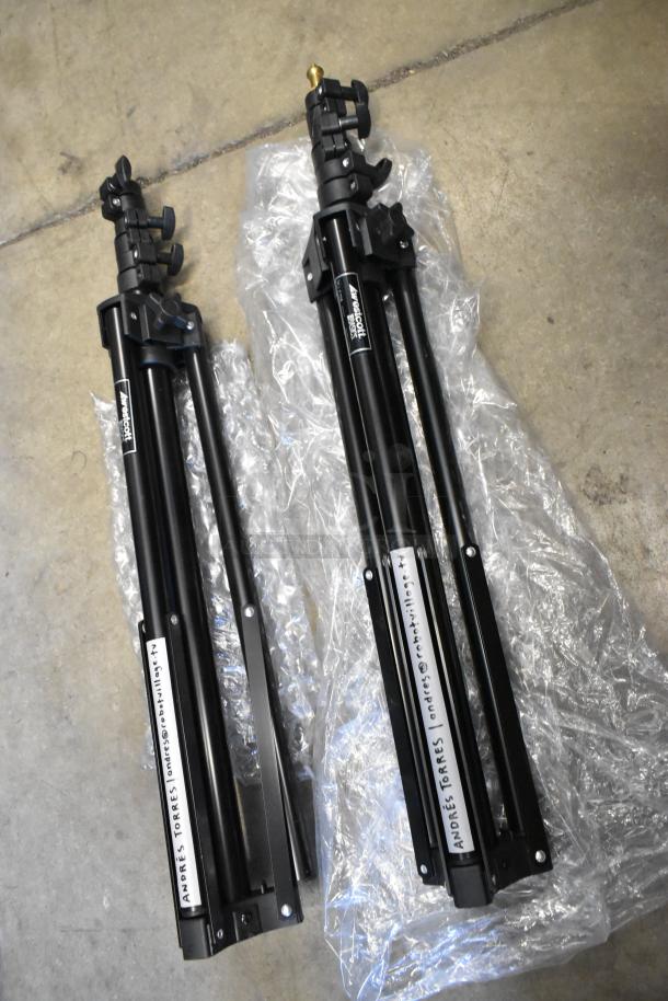 Two Westcott Basics stands, black, foldable, in good condition, placed on bubble wrap. Marked with owner's contact.