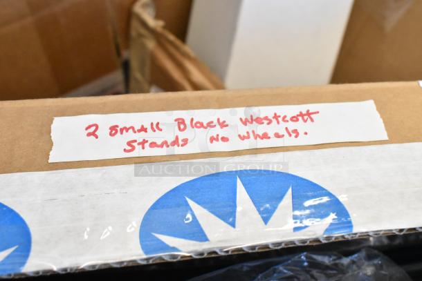 Cardboard box labeled "2 small black Westcott stands, no wheels" with visible tape and logo.