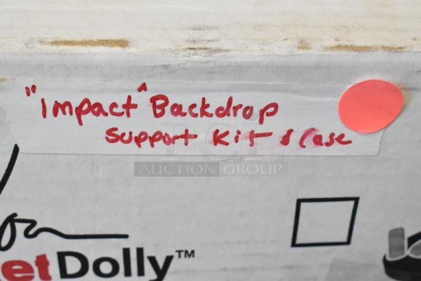 "Impact" Backdrop Support Kit case, labeled in red marker, cardboard box with wear, bright pink dot sticker visible.