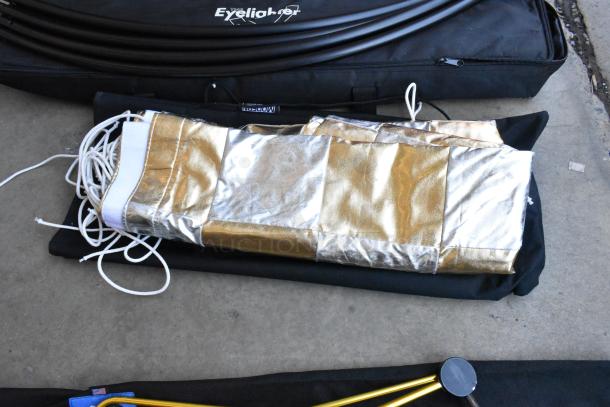 Umbrella and light gear with metallic fabric holder, black carrying case marked "Eyeblinder," includes white cords.