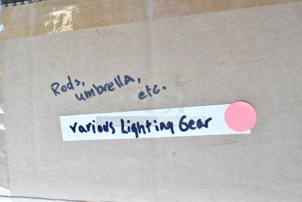 Cardboard box labeled "Rods, umbrella, etc." and "Various Lighting Gear," indicating contents. Pink sticker present.