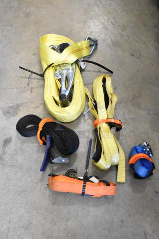 Lot of assorted ratchet straps in various colors, coiled and secured with ties, placed on a concrete floor.