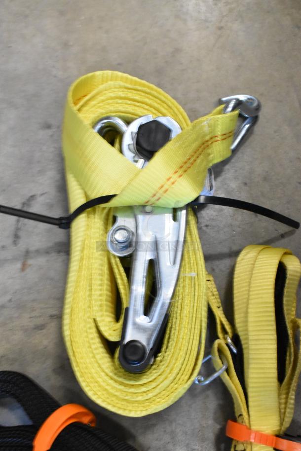 Lot of yellow ratchet straps in poly bin, featuring metal buckles and hooks, good condition, ideal for securing cargo.