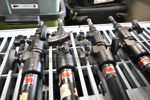 Four Matthews Studio Equipment frame pieces, black metal, with adjustable knobs and visible brand labels, on storage rack.