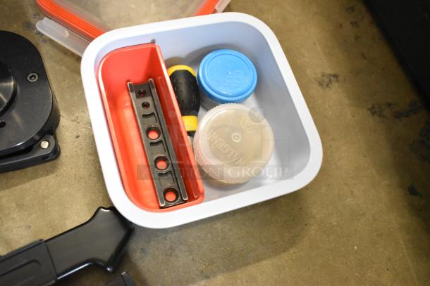 Poly bin with assorted parts and pieces, including a screwdriver, brackets, and plastic caps. Condition appears used.