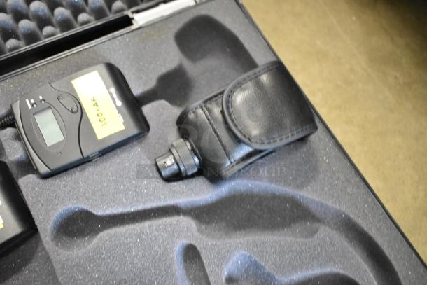 Two Sennheiser SK100 bodypack transmitters in a carrying case, with visible model label "100-AK," in excellent condition.