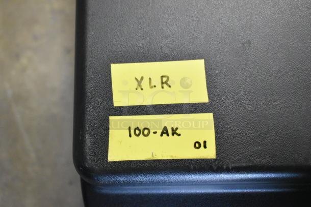 Two Sennheiser SK100 bodypack transmitters with visible yellow labels marked "XLR" and "100-AK 01".