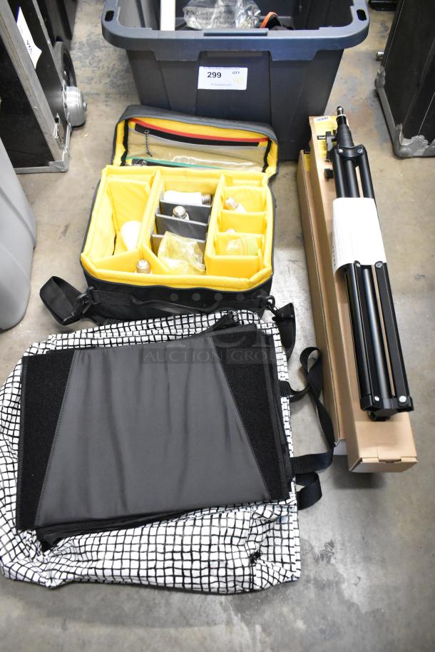 Lot of items in a poly bin: includes an impact light stand, lightbulbs in a yellow compartmented bag, and fabric.