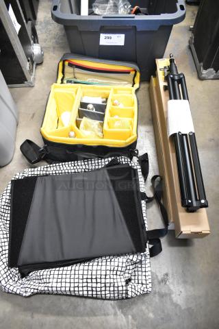 Lot of items in a poly bin: includes an impact light stand, lightbulbs in a yellow compartmented bag, and fabric.