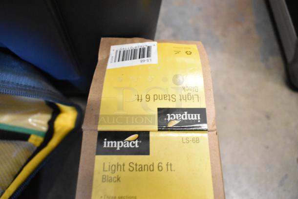 Impact Light Stand 6 ft, black, model LS-6B label in a poly bin with lightbulb and fabric, good condition.