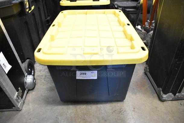 Poly bin with yellow lid labeled "299," containing an Impact light stand, lightbulb, and fabric. Auction lot includes various items.