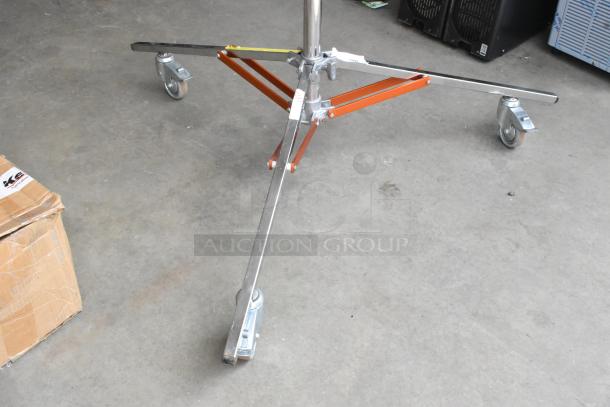 Matthews Studio Equipment tripod on casters, stainless steel legs, orange supports, good condition, industrial use.