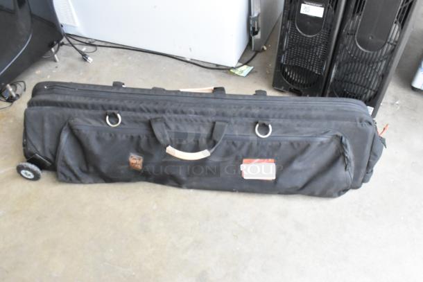 Matthews Studio Equipment tripod on casters in a black soft case, featuring handles and visible logos, in good condition.