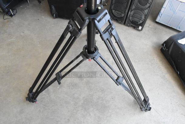 Soom tripod with sturdy black legs in good condition, set on concrete floor. Includes soft carrying case.
