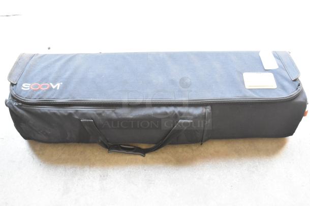 Soom tripod in black soft case with branded logo, showing minimal wear. Sturdy handles for easy transport.