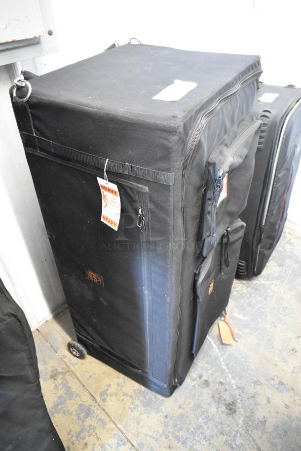 Black Porta Brace case with wheels and multiple zippered compartments. Visible heavy lift caution tag. Good condition.