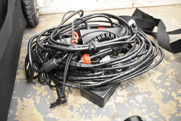Coiled cables of Kessler Filmmaking Unit with Power Sonic PS-1270F1 battery, set on a concrete floor.