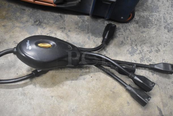 Black power strip with multiple black cables on a concrete floor, labeled "poetry in action."