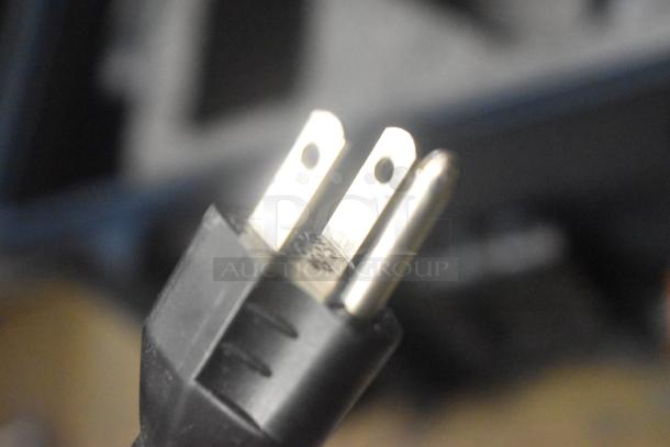 Close-up of a three-prong plug connector against a blurred background. No visible markings or labels.
