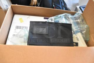 Box of assorted items including various lighting gear, a black pouch with a label, and packaged materials, suitable for resale.