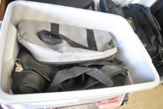 Poly bin filled with various lighting clamps in gray and black bags; good condition, ideal for equipment setup.