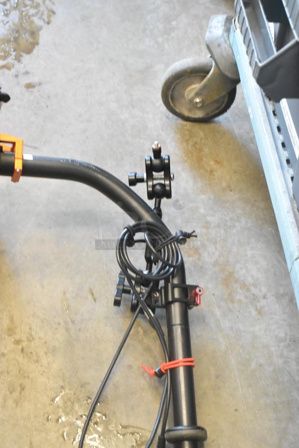 Metal frame with black tubing, featuring adjustable clamps and attached cables. Appears in used condition, suitable for equipment mounting.