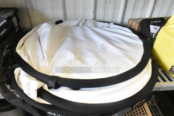 Folded Luma Pop Unit with white fabric and black edges, in good condition, placed on a metal shelf.