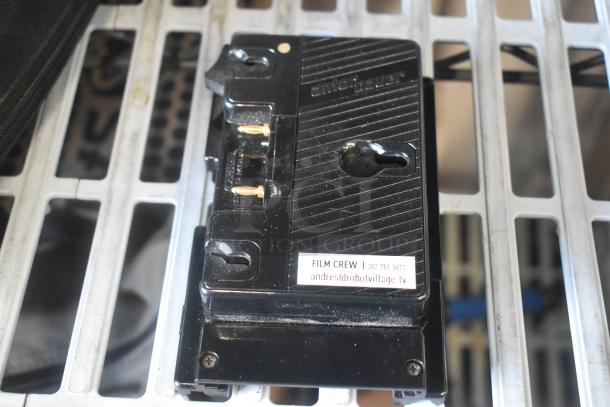 V Mount to Gold Mount Adapter, Anton/Bauer brand, black, slight wear. Label reads "FILM CREW | 302-753-3672 | andres@robotvillage.tv."