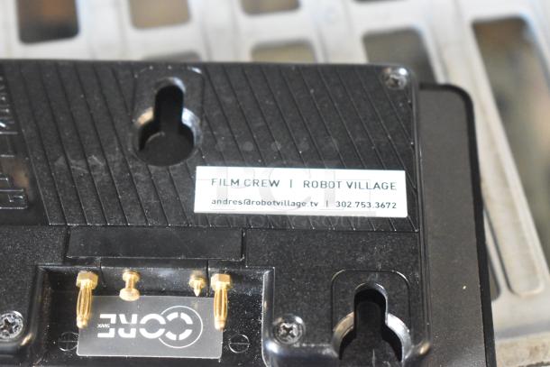 V Mount to Gold Mount Adapter, black, with contact pins and label reading "Film Crew | Robot Village," minor wear visible.