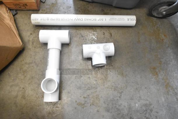 Lot of various PVC pipe fittings and a pipe labeled "1.5 SCH40 DWV PVC120 330 PSI" on a concrete floor.