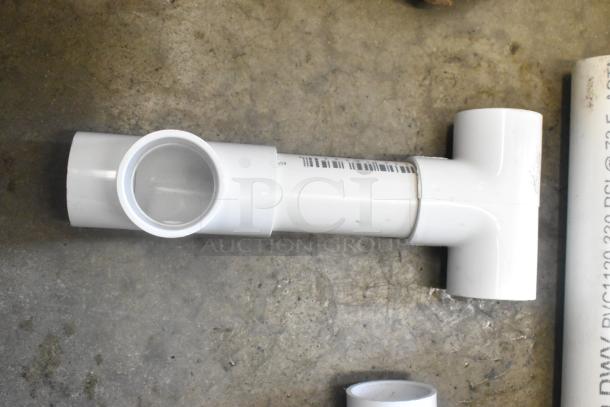 Lot of PVC pipe fittings in poly bin. Includes T-fitting in good condition with barcode label. Ideal for plumbing projects.