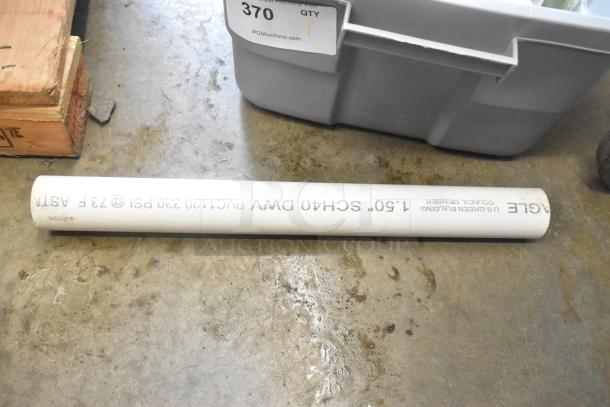 PVC pipe labeled "SCHEDULE 40 DWV" next to a gray poly bin in auction lot; industrial setting.