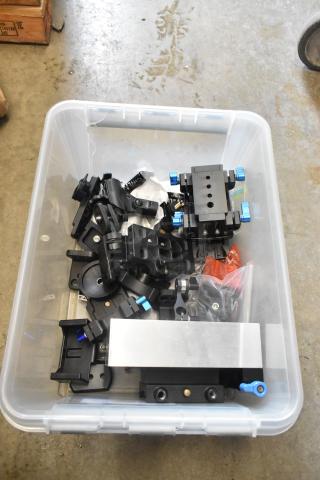 Poly bin with assorted camera attachment gear, various black metal brackets, mounts, and hardware. Good condition.