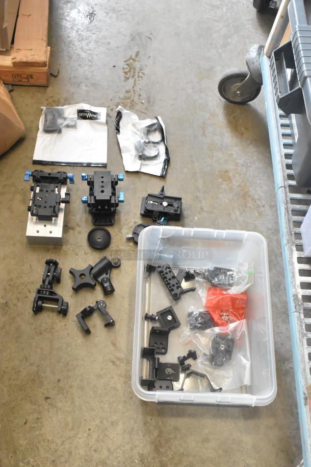 Lot of camera attachment gear in poly bin, includes various mounts and components. Good condition, ideal for equipment setup.