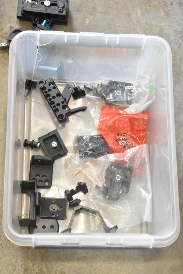 Poly bin containing various camera attachment gear, including brackets, screws, and mounts. Some items in bags, labeled "MAX 40W."