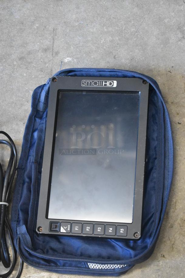 Small HD Monitor in protective case, features F1-F5 buttons, slight wear visible. Ideal for portable video setups.